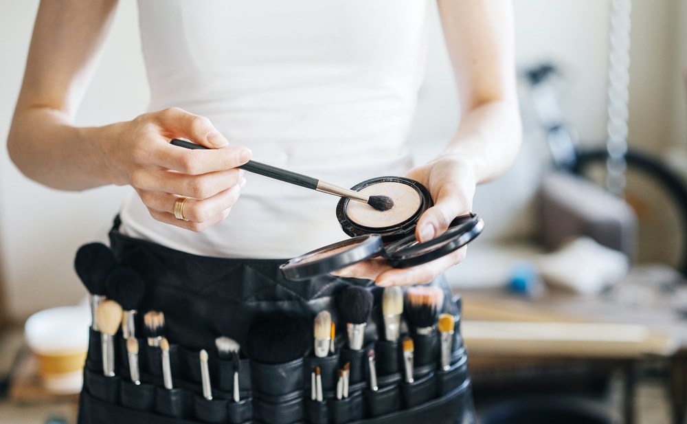 makeup artist with belt bag and makeup brushes