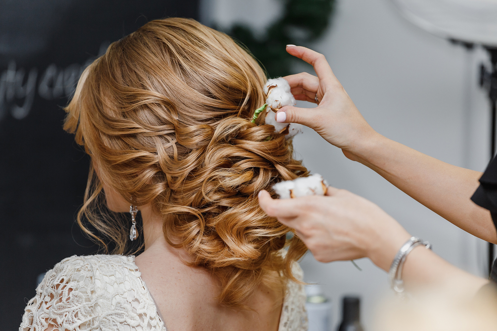 Hairstylist helping with bride's hair