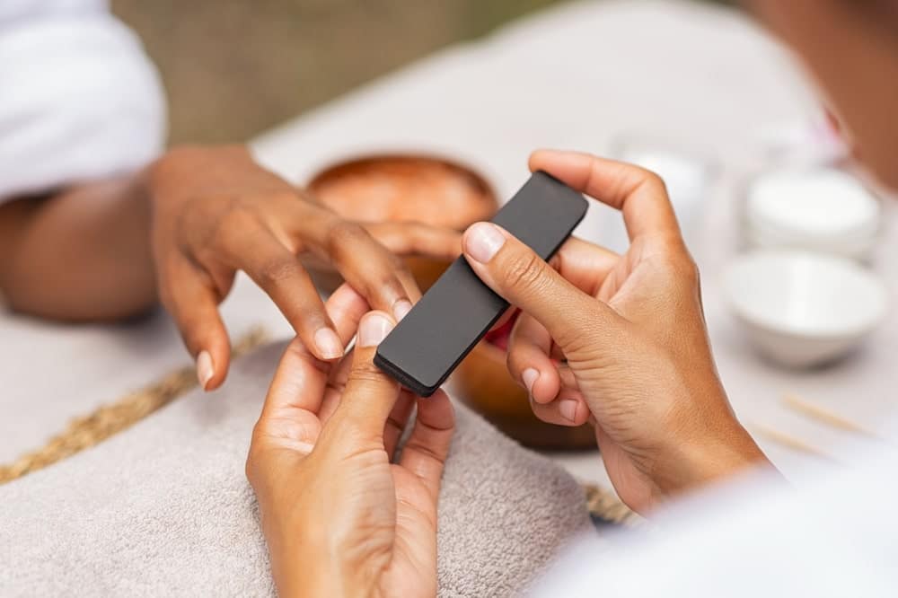 woman getting a manicure and her nails filed