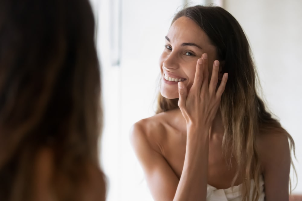 woman looking in a mirror and looking at her skin