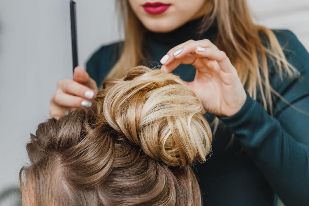 woman fixing the top of a woman's bun