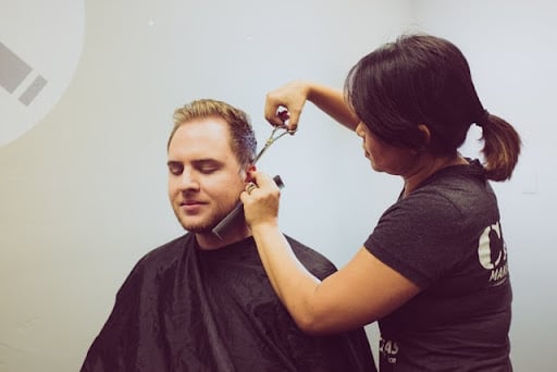 Student cutting man's hair.