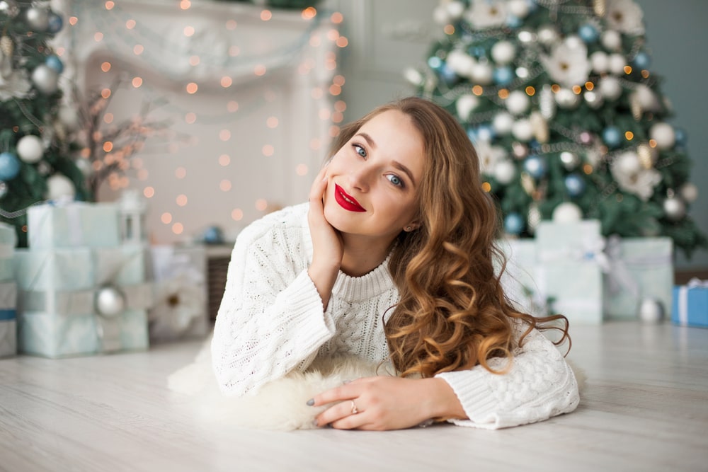 woman with beautiful hair smiling with a decorated tree in the background